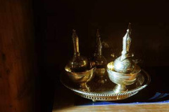 Water vessels for the sharing of merit shine in the early morning sun on the base of the main sala shrine.