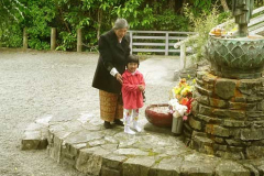 Grandma giving instruction on making offerings to the standing Buddha shrine in the courtyard.