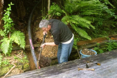 Cutting across the moat of emptiness - one pipe. Chris hard at work burying the beast.