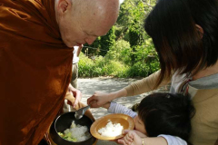 Ajahn Sucitto bending low for an offering of rice.