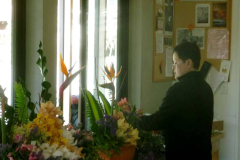 Nuk gives concentrated attention to create beautiful flower arrangements for Kathina.