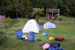 A typical camp site with a small shelter. The stairs at right lead up to the sink and water pump. The ground is (almost) flat.