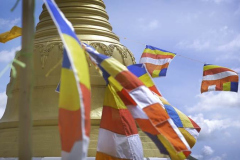 Flags at the stupa flying across a blue sky.