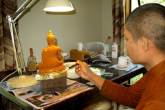 Ajahn Kongrit applying the first layer of gold leaf to the buddha.