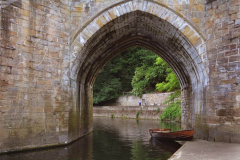 A boat rests in the River Wear next to Durham Cathedral.