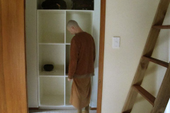 Venerable Kondanyo inspecting the new monks lockers in the Bhikkhu vihara. The stairs to the loft over the common room to right.