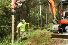 The first retaining wall post being driven in. Brian on the level Kevin in the digger.
