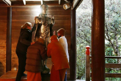 Monks and men move the Buddha to a higher place.
