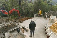 The old stone walls and concrete slab have been removed. The digger prepares the ground.