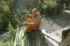 Ajahn Joe working on local broom material experiment #11 - nikau fronds; to be mixed with coconut palm fronds.
