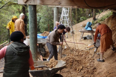 The vihara basement gets a team effort in leveling the floor ready for a concrete slab.