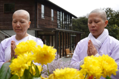 Viphavadee and Noi at the standing buddha rupa in the courtyard.