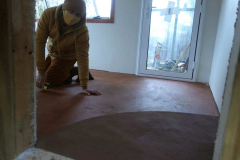 A view through the firewood cupboard into the new kuti. Venerable Dhammavasa is preparing the floor for a second coat of varnish.