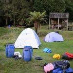 A typical camp site with a small shelter. The stairs at right lead up to the sink and water pump. The ground is (almost) flat.