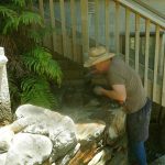 Simon applies the final grouting to the end of the stair wall. It is bright enough for a sun hat!