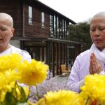 Viphavadee and Noi at the standing buddha rupa in the courtyard.