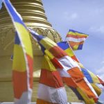 Flags at the stupa flying across a blue sky.