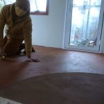A view through the firewood cupboard into the new kuti. Venerable Dhammavasa is preparing the floor for a second coat of varnish.