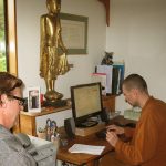 Venerable Kondanyo organising a flight for Ajahn Kongrit with Drew all ready as steward.