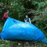Ryan and Bruce hauling a tarp full of autumn leaves.