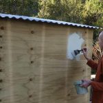 Venerable Buddhisaro up on minimal scaffold giving colour to the wood store of the new monk kuti.