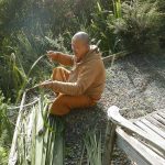 Ajahn Joe working on local broom material experiment #11 - nikau fronds; to be mixed with coconut palm fronds.