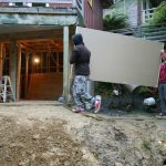 Cosmo and Ryan carrying the gib board down from the forecourt to the new Garden kuti.