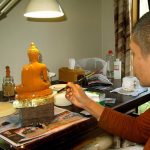 Ajahn Kongrit applying the first layer of gold leaf to the buddha.