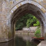A boat rests in the River Wear next to Durham Cathedral.