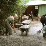Julienne and Katie-Jayne shoveling gravel to go on the access track and service area under the workshop.