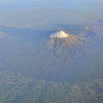 The full circular glory of Mt. Taranaki casts a long early morning shadow.