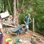 The upper kuti is much steeper; not such an easy site. Clare delivers floor insulation while John puts concrete in the foundations.