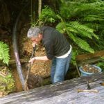 Cutting across the moat of emptiness - one pipe. Chris hard at work burying the beast.