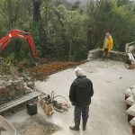 The old stone walls and concrete slab have been removed. The digger prepares the ground.
