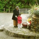 Grandma giving instruction on making offerings to the standing Buddha shrine in the courtyard.