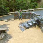 Adding yet another nice touch to his beautiful stone walled garden Simon rakes out the first layer of white stone.