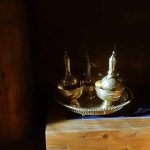 Water vessels for the sharing of merit shine in the early morning sun on the base of the main sala shrine.
